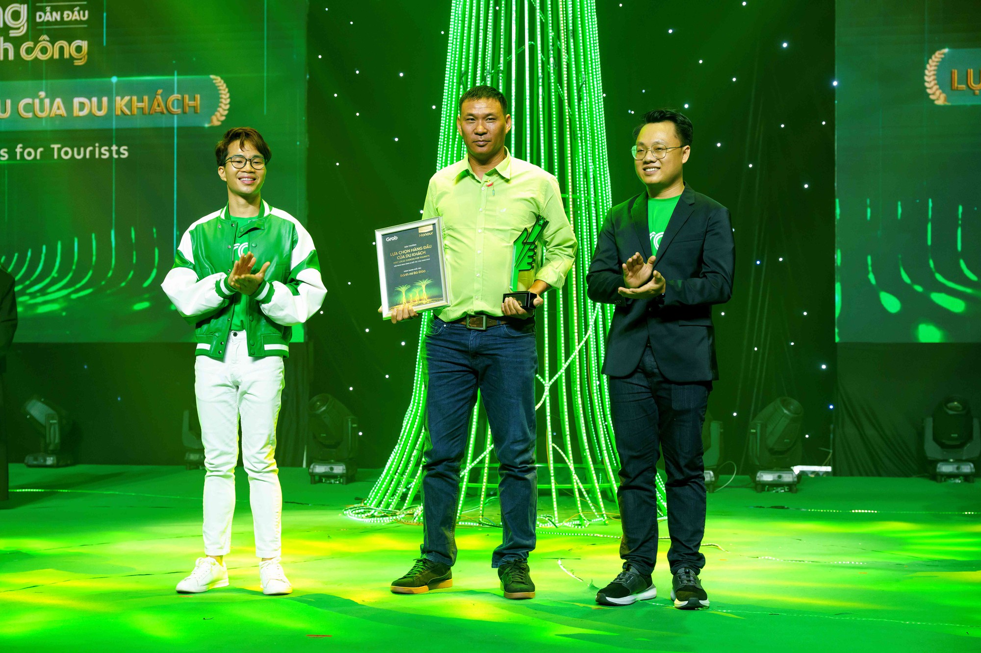 Anh Phạm Tân Sinh (giữa), đại diện bánh mì bà Đào nhận giải &quot;Lựa chọn hàng đầu của du khách&quot; từ Grab